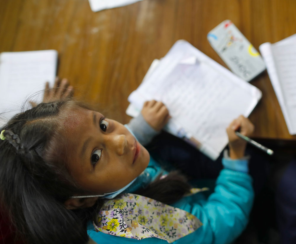 A young girl does her homework in Nepal